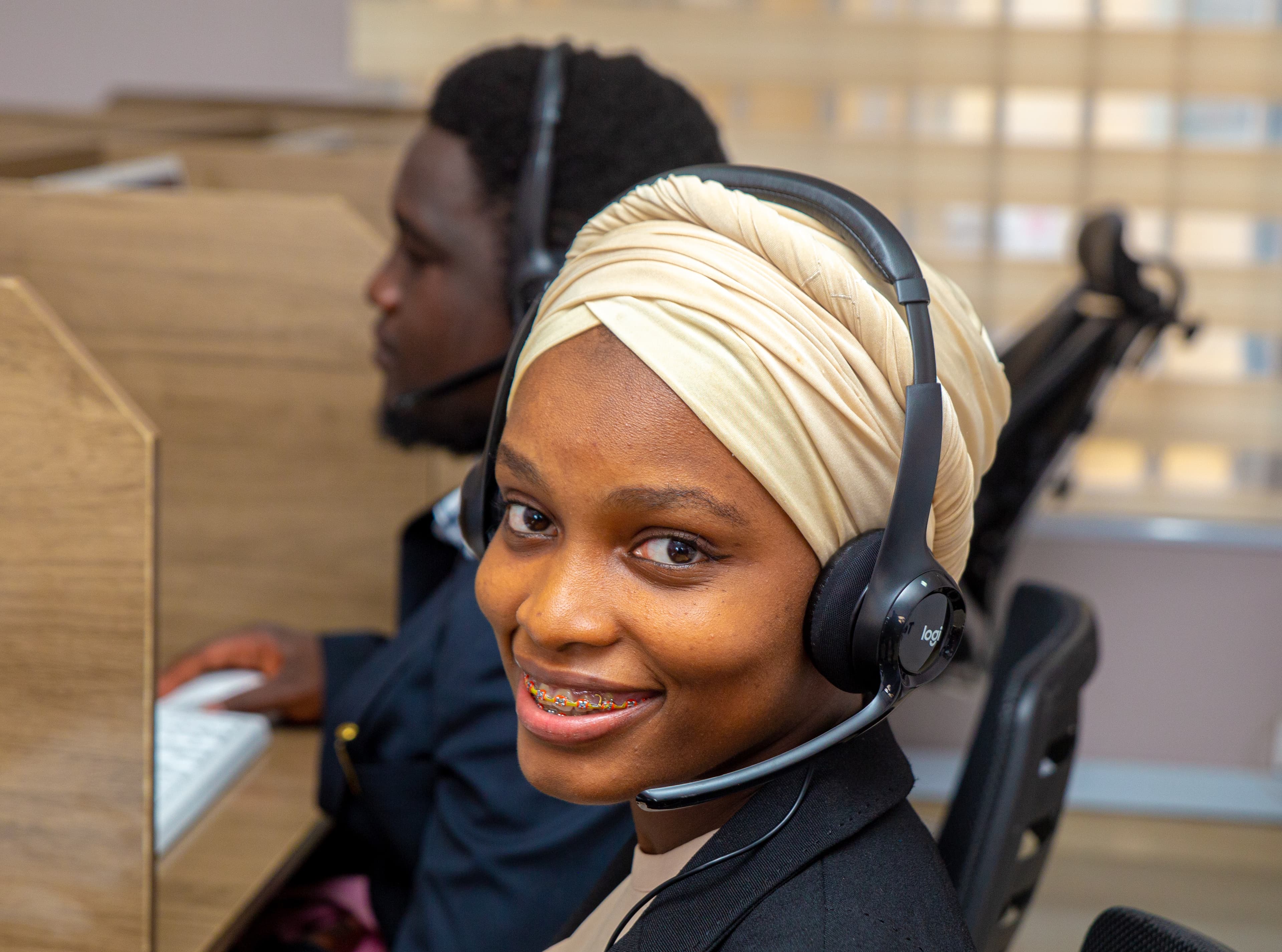 TeleConnect agent with a headset at her desk on the contact center floor